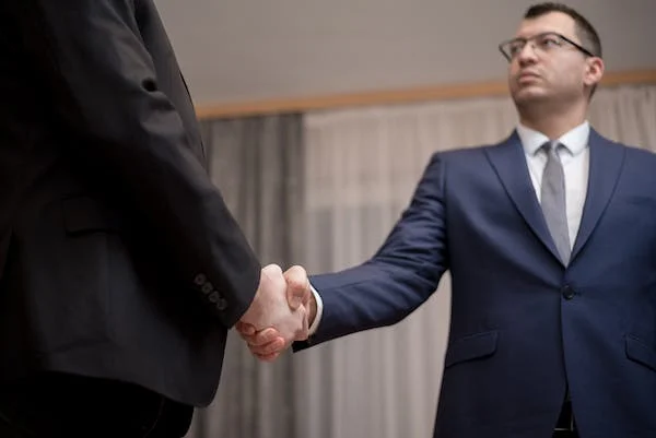 Una persona de traje que le da la mano a otra persona de traje simboliza el proceso de soborno