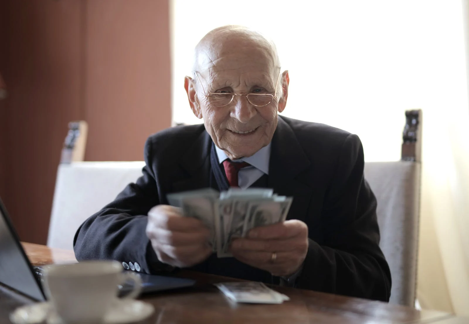 Una persona con traje contando dinero, que simboliza el lavado de dinero y los delitos financieros