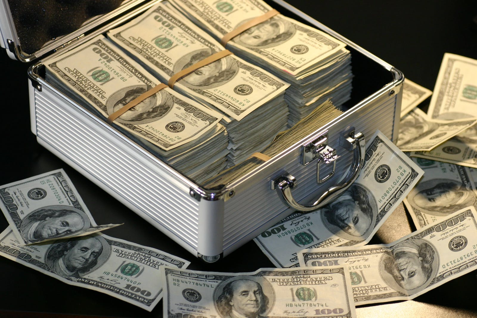 Una imagen que muestra una pila de dinero en efectivo con varias obras de arte en el fondo, que representan el problema del lavado de dinero del arte en los Estados Unidos bajo las regulaciones AMLA 2020.